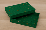 A sleek green rectangular Lokta paper box with clean edges and a matte, fibrous finish, resting on a smooth surface under diffused lighting.