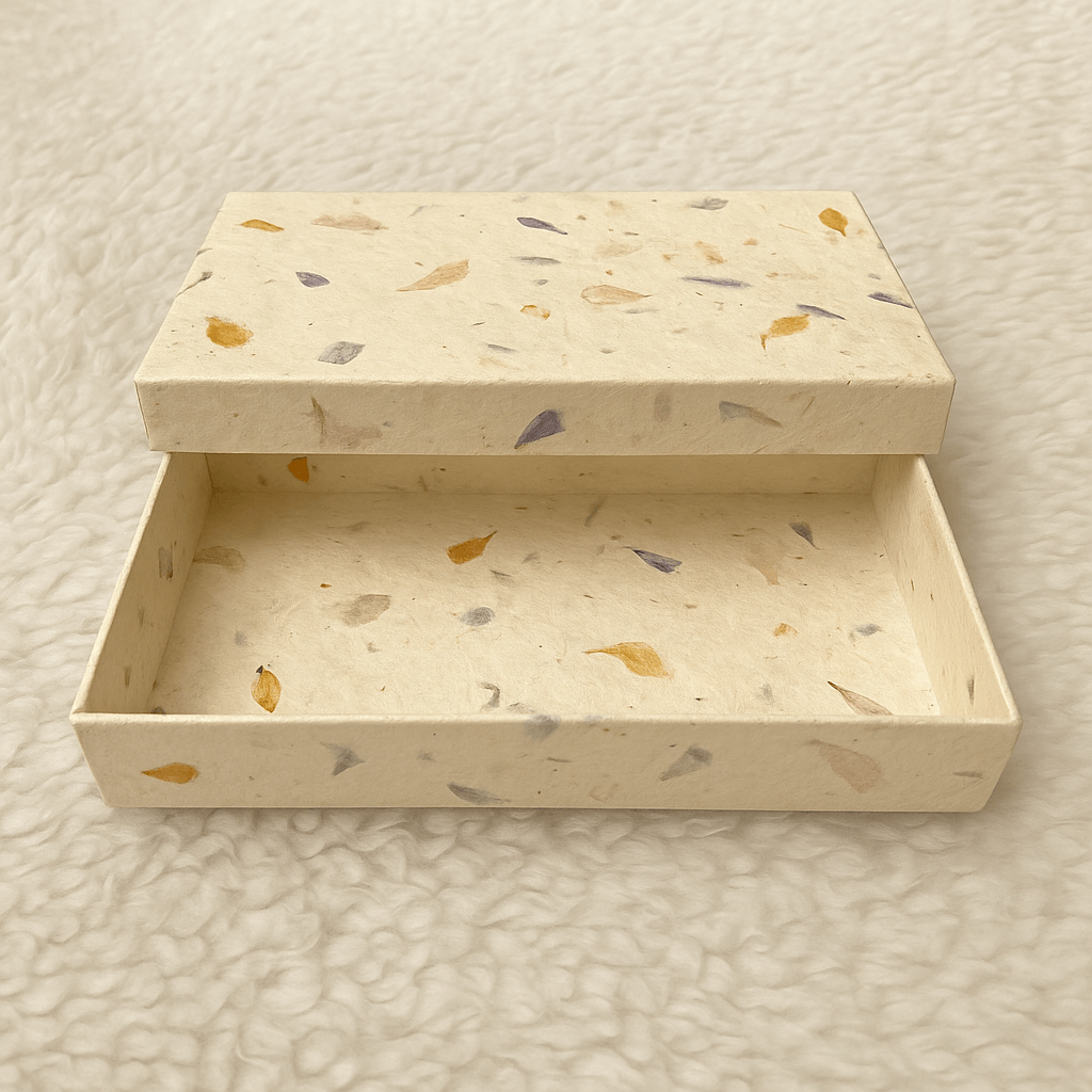 A handcrafted rectangular keepsake box made from natural Lokta paper embedded with dried flower petals and leaves, displayed open on a white surface.